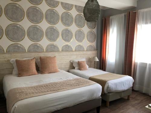 a bedroom with two beds and a wall with plates at Family Golf Hotel in Royan