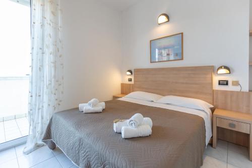 een slaapkamer met een groot bed en handdoeken bij Hotel Globus in Rimini