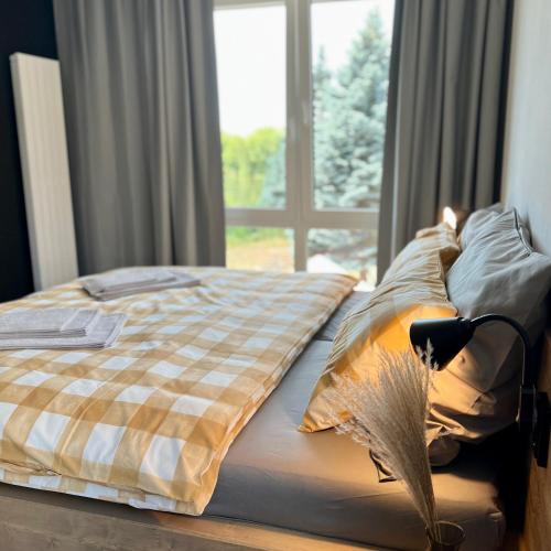 a bed with a checkered blanket and a window at Penzion Racek in Tuchlovice