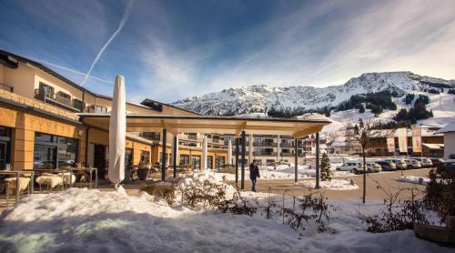a building in the snow with mountains in the background at Panoramahotel Oberjoch in Bad Hindelang