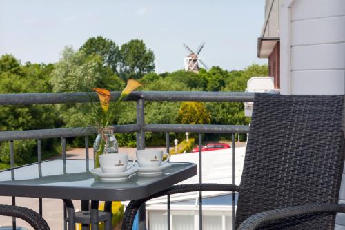 a table with two cups and a vase on a balcony at Hotel Novum in Hinte
