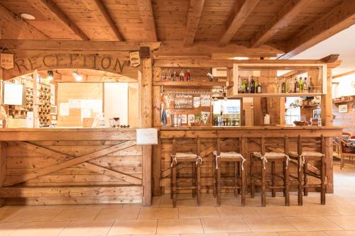 un bar de madera con taburetes en un restaurante en Hotel Vescovi en Asiago