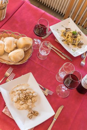a red table with plates of food and glasses of wine at Hotel Vescovi in Asiago