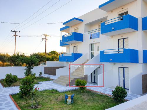 a house with blue balconies and a yard at Pittas Studios in Kardamaina