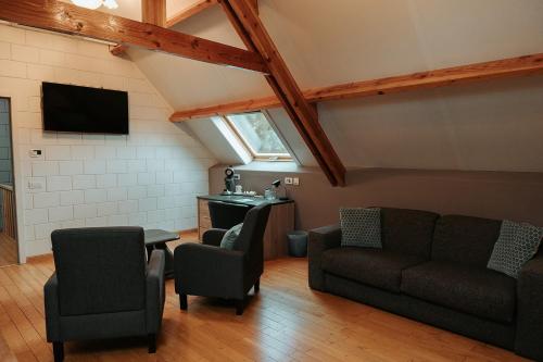 a living room with a couch and chairs and a tv at Hotel Ter Zuidhoek in Roeselare