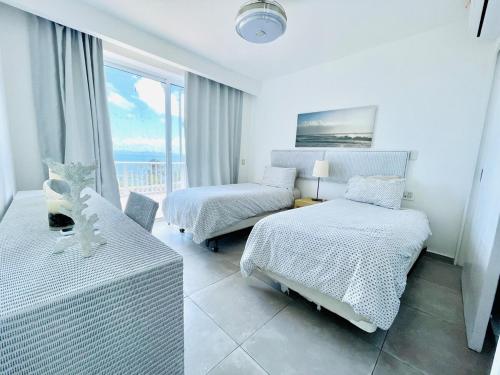 een witte slaapkamer met 2 bedden en een raam bij Paradise Retreat Peace Relaxation in Santa Bárbara de Samaná