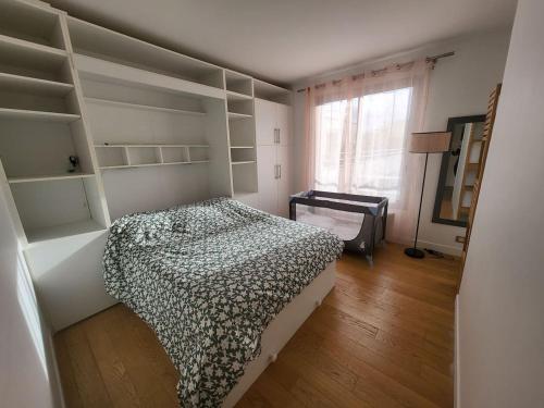 ein Schlafzimmer mit einem Bett, Regalen und einem Fenster in der Unterkunft T2 charmant rue de Commerce in Paris