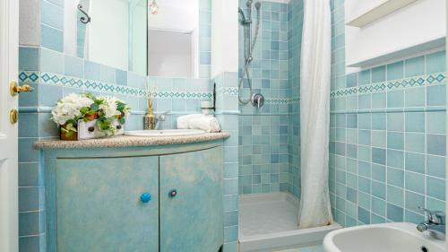 a blue tiled bathroom with a sink and a shower at VILLA STELLA 6, Emma Villas in Arzachena