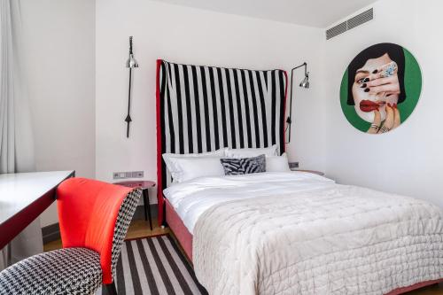 a bedroom with a bed and a red chair at H15 Boutique Hotel, Warsaw, a Member of Design Hotels in Warsaw