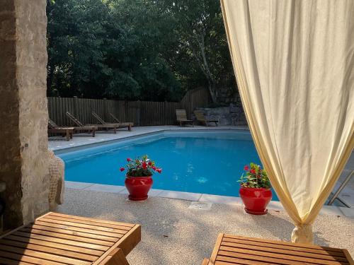 une piscine avec deux plantes en pot et deux bancs dans l'établissement Les Chalets de Labeaume, à Labeaume