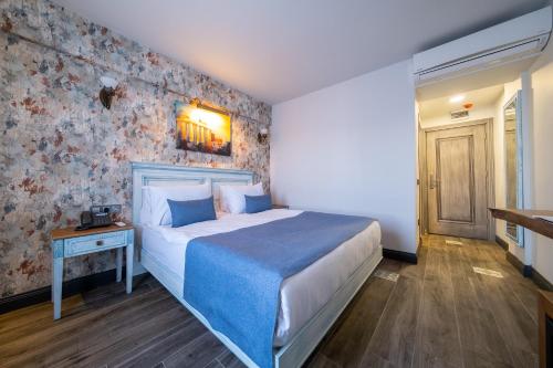 a bedroom with a large bed with a blue blanket at Assos Troy Port Hotel in Ayvacık