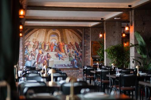 a dining room with tables and chairs and a painting on the wall at Assos Troy Port Hotel in Ayvacık