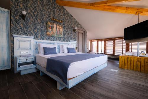 a bedroom with a large bed and a tv at ASSOS TROY PORT HOTEL (+8) in Ayvacık