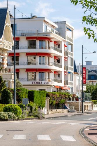 a white building with red balconies on a street at Family Golf Hotel in Royan