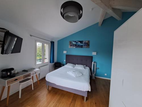 1 dormitorio con paredes azules, 1 cama y escritorio en Hôtel L'Auberge Canaulaise en Lacanau-Océan