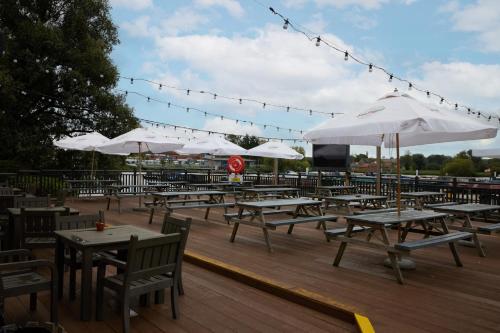 Ein Haufen Tische und Sonnenschirme auf einem Deck in der Unterkunft The Quays by Greene King Inns in Northampton