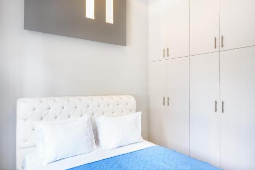 une chambre blanche avec un lit avec des armoires blanches dans l'établissement Kazi Home 3, à Athènes