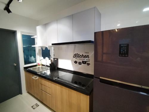 a kitchen with a refrigerator and a counter top at Double Nine Homestay - Sri Indah Condominium in Sandakan