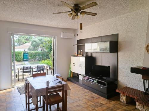 uma sala de estar com uma mesa de jantar e uma televisão em Mini villa jardin 50 m plage em Borgo