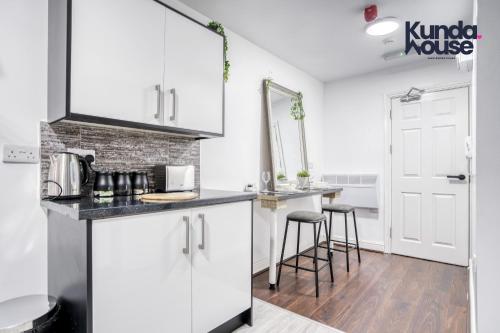 uma cozinha com armários brancos e um balcão com bancos em Cosy Apartments - City Living Made Elegant - em Birmingham