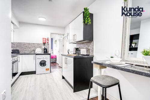 cocina con armarios blancos, lavadora y secadora en Cosy Apartments - City Living Made Elegant -, en Birmingham