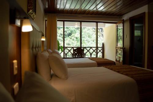 a hotel room with two beds and a large window at Santuario Machupicchu in Machu Picchu