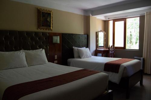 a hotel room with two beds and two windows at Santuario Machupicchu in Machu Picchu
