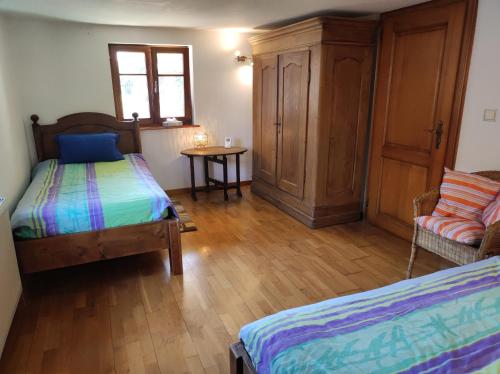 NiederroedernにあるPetite maison alsacienne dans un village au calmeのベッド2台、椅子、テーブルが備わる客室です。