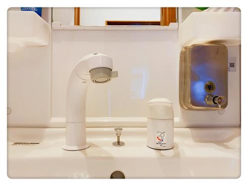 a bathroom sink with a white faucet and a cup at TOKYO/Shinjuku & Shibuya 10mins/5mins walk to subway stiaon/Kichijoji 15mins/Shimokitazawa 5mins/Louis House in Tokyo