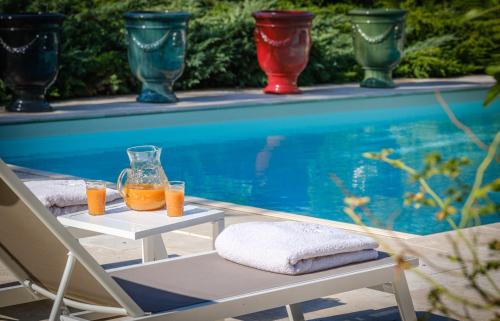 a table with two glasses of orange juice next to a swimming pool at Domaine de la Blonnerie in Feings