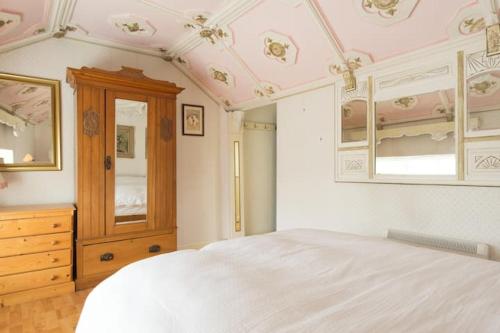 a bedroom with a white bed and a wooden dresser at Niamh's Seaside Cottage in Kinvara