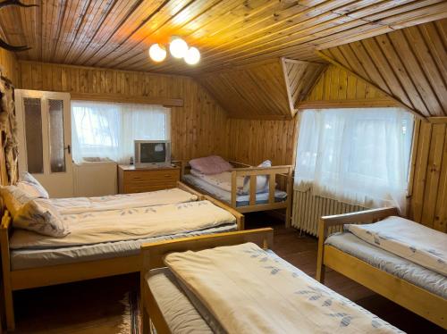 1 dormitorio con 3 camas en una habitación de madera en CABANA CLAUDIA en Petroşani