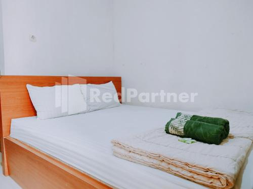 een bed met een houten hoofdeinde en een groen kussen bij Calida Hotel Mitra RedDoorz near Alun Alun Wonosari in Wonosari