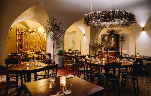 een restaurant met tafels en stoelen en een kroonluchter bij Kounický dvůr in Dolní Kounice