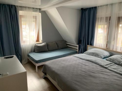 a bedroom with two beds and a couch and windows at Gasthaus L&A Kunz in Dümpelfeld