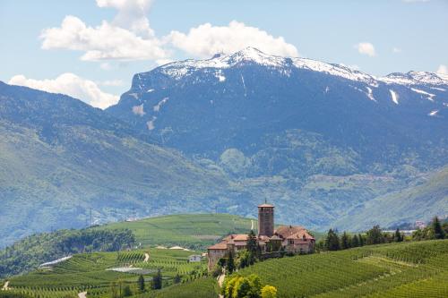 uma casa numa colina com uma montanha ao fundo em Appartamento Le Colonne - Relais Villa Quercia em Tassullo