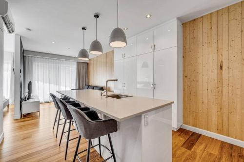 a kitchen with white cabinets and a counter with bar stools at Initial / Ilot / Downtown Québec in Quebec City