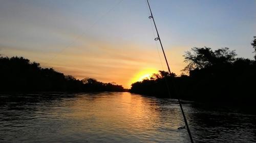 een uitzicht op de zonsondergang vanaf een boot op een rivier bij Rancho Terra in Dourados