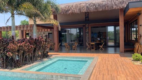 a villa with a swimming pool in front of a house at Rancho Terra in Dourados