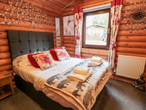 a bedroom with a bed in a log cabin at 10 Water's Edge in Morpeth