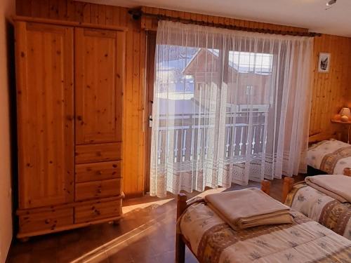 une chambre avec deux lits et une grande fenêtre dans l'établissement Appartement 52m² pour 5 pers proche pistes, accès facile, animaux admis – Le Grand-Bornand Village - FR-1-467-77, au Grand-Bornand