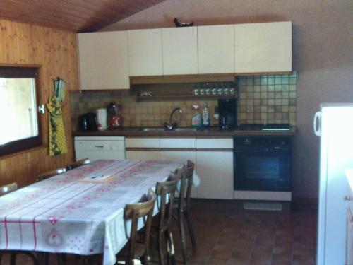 une cuisine avec une table avec des chaises et des armoires blanches dans l'établissement Appartement 6 pers. avec jardin, proche pistes, animaux admis, Le Grand-Bornand Village - FR-1-467-80, au Grand-Bornand