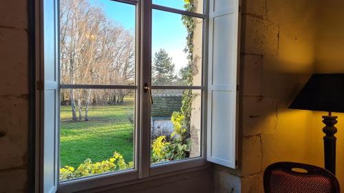 a window with a view of a green yard at Domaine de la Blonnerie in Feings