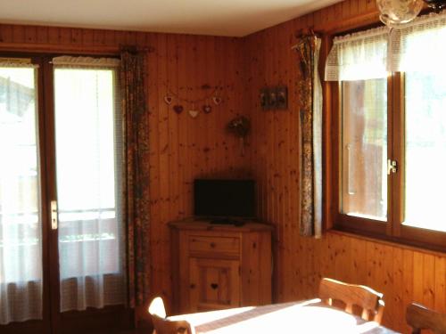d'une salle à manger avec une télévision, une table et des fenêtres. dans l'établissement Appartement cosy 6 pers - proche pistes, navette, animaux admis - Grand-Bornand Village - FR-1-467-78, au Grand-Bornand