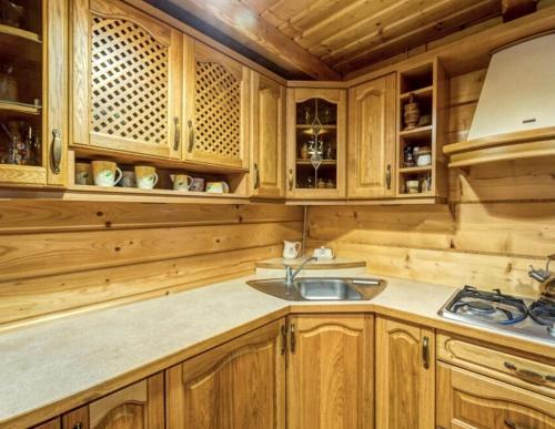 a kitchen with wooden cabinets and a sink at Bacówka Polanki in Obidowa