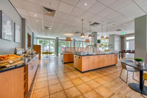 a large kitchen with a counter and a cafeteria at ibis Hotel Frankfurt Messe West in Frankfurt