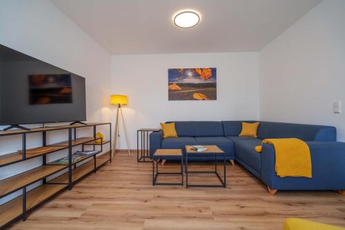 sala de estar con sofá azul y TV en HERZstück Erzgebirge, en Olbernhau
