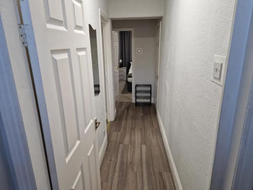 a hallway with a white door and wooden floors at Birtley's Amethyst, 3 bedroom Apt ,sleeps 6 Guest in Birtley