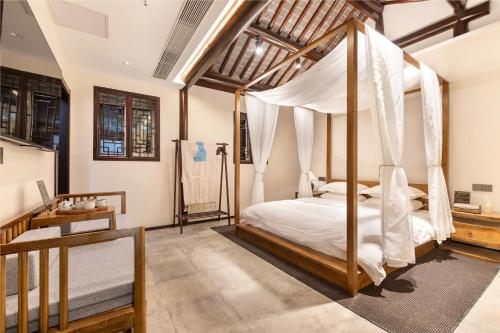 a bedroom with a canopy bed and a desk at Yangzhou Aihehua Boutique Homestay in Yangzhou