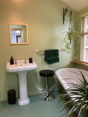 a bathroom with a sink and a stool in it at Woodland Retreat, Market Lane, Blundeston, Lowestoft in Blundeston